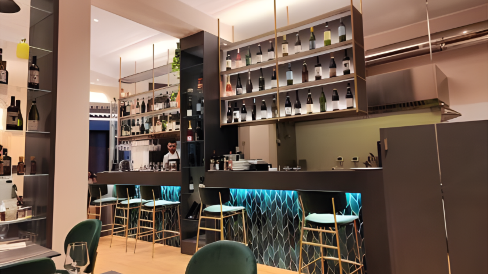 Il bancone bar di O'Lusso, con piastrelle teal e mensole in ottone